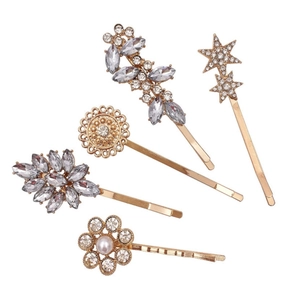 Detailed view of five gold-toned crystal hair clips featuring star and floral motifs