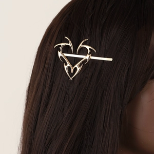 Vintage gold thorn heart hair clip made of polished metal shown on dark hair