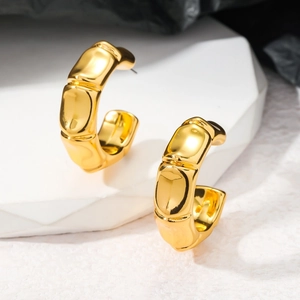 Vue détaillée macro de boucles d'oreilles dorées style bambou avec une finition miroir polie