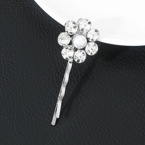 Macro detail of silver flower hair clip with sparkling rhinestones and white pearl center