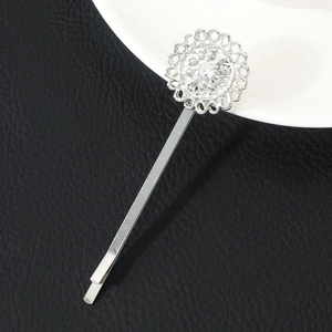 Detailed macro view of silver flower hair pin with rhinestones on black leather surface