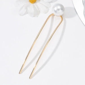 Detail view of a gold U-shaped hairpin featuring a large lustrous white pearl accent