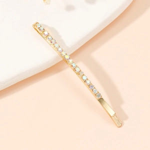 Détail d'une pince à cheveux dorée ornée de strass AB irisés sur support texturé