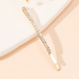 Détail d'une barrette fine dorée ornée de strass en cristal étincelants