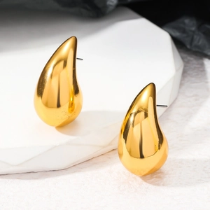 Détail macro de boucles d'oreilles gouttes dorées polies sur présentoir géométrique