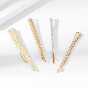 Set di quattro fermagli per capelli dorati con strass scintillanti su sfondo bianco