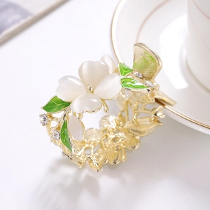 Pince à cheveux fleurie dorée avec pétales en opale blanche et détails de feuilles