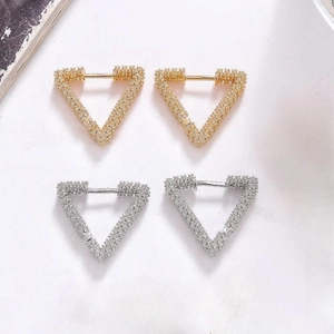 Detailed view of triangular hoop earrings with sparkling texture in gold and silver