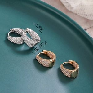 Boucles d'oreilles en or et argent en forme de U avec zircons sur un plat