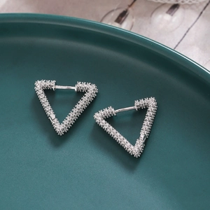 Detail view of silver triangle huggie earrings with fine textured finish on dark tray