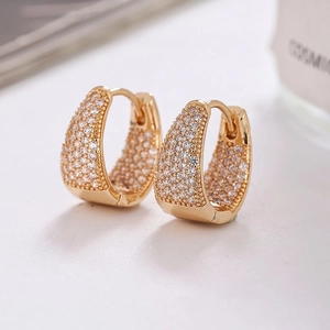 Gros plan de boucles d'oreilles dorées en U avec micro-pavage en zircons et fermoir