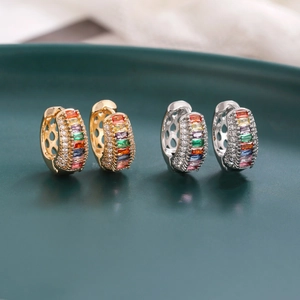 Détail de créoles en zircon arc-en-ciel avec micro-pavage de pierres sur plateau vert foncé