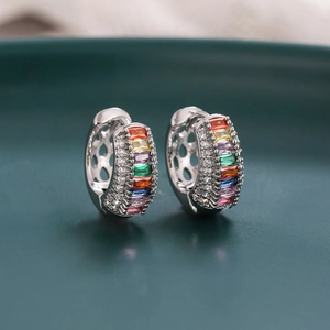 Vue macro de boucles d'oreilles créoles avec zircons arc-en-ciel et finition argent polie