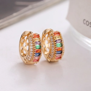 Détails de boucles d'oreilles créoles dorées avec zircons colorés et cristaux fins