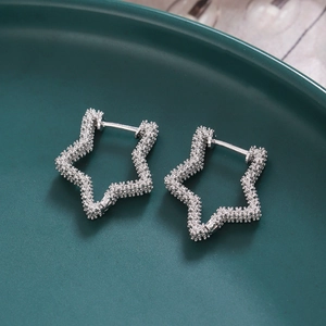 Macro shot of silver-colored star earrings with sparkling texture on a dark ceramic background