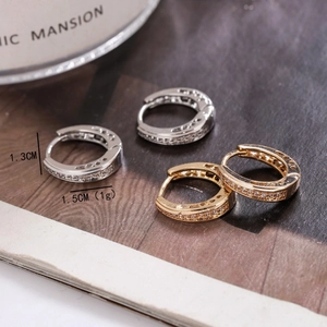 Boucles d'oreilles créoles dorées et argentées avec zircons sur fond de magazine