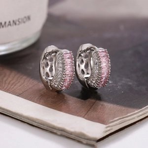 Détail macro de boucles d'oreilles huggie avec zircon rose et pavé de diamants