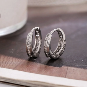Gros plan de boucles d'oreilles créoles argentées avec zircon micro-pavé sur magazine