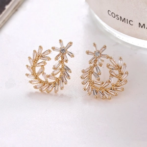 Detail of gold leaf earrings featuring marquise and round cubic zirconia in a half-moon curve