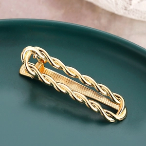 Modern twisted gold metal hair clip with a minimalist geometric textured design