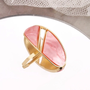 Détail d'une bague dorée ornée de résine à texture de marbre rose aux formes géométriques