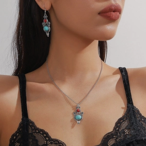 Bohemian silver necklace and turquoise earrings set worn by model against black lace background