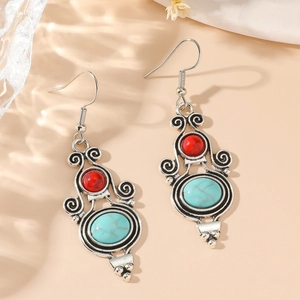 Pendientes bohemios de plata con cuentas turquesas y rojas sobre fondo texturizado