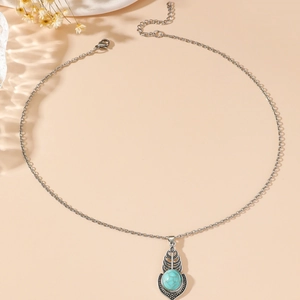 Bohemian style necklace with turquoise oval pendant and intricate silver flower detailing