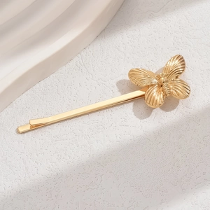 Gros plan d'une pince à cheveux papillon dorée Y2K avec détails de texture radiale