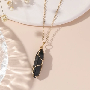 Vue détaillée d'un pendentif en cristal hexagonal noir enveloppé de fil doré artisanal