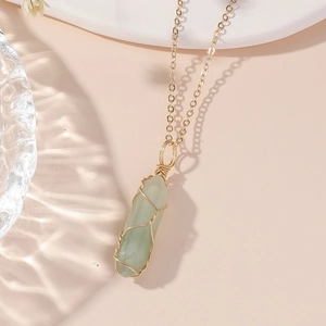 Vue détaillée d'un pendentif en cristal vert hexagonal avec un fil d'or finement enroulé