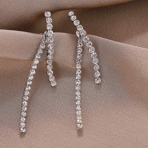 Detailed view of silver tassel earrings with sparkling rhinestones on silk fabric