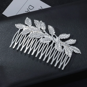 Close-up of silver leaf hair comb with detailed metal carvings on black leather