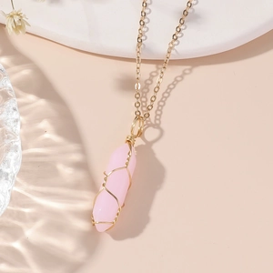 Collier en quartz rose hexagonal fait main avec fil doré sur un support minimaliste