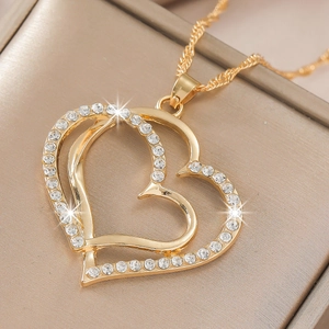 Close-up of golden double heart pendant necklace with rhinestones on textured gift box