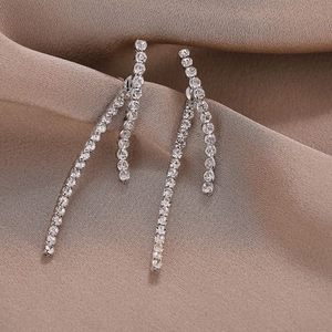 Macro view of geometric silver tassel earrings with sparkling rhinestones on satin