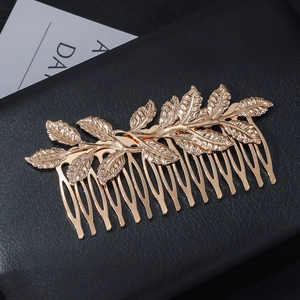 Detailed close-up of champagne gold leaf hair comb featuring intricate metallic textures