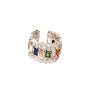 Vue macro d'une bague large argentée luxueuse avec zircons colorés et design évidé ondulé