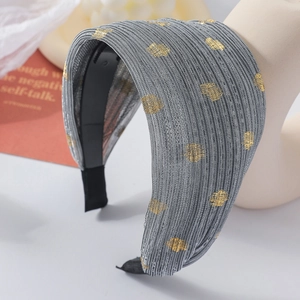 Gros plan d'un serre-tête large en tissu plissé gris avec motifs à pois dorés