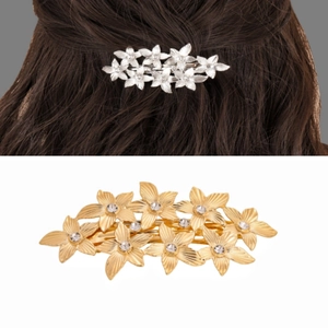Detail of leaf-shaped metal hair clip with sparkling crystals in gold and silver finish