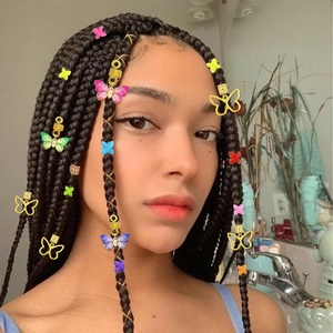 Détail de bijoux de cheveux pour dreadlocks avec papillons en résine et spirales dorées