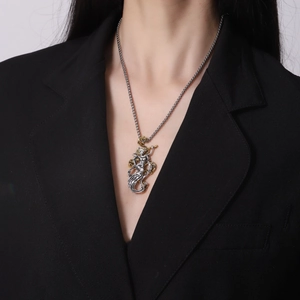 Pendaglio bicolore in oro e argento con catena indossato su un abito nero