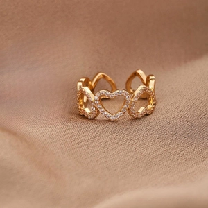 Vista macro di un anello regolabile dorato con motivi a cuore e zirconi brillanti