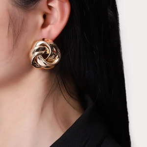 Retro golden twisted sphere stud earrings with a polished finish worn by a model