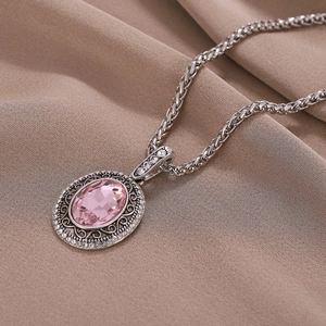 Collier vintage avec pierre rose et filigrane argenté sur tissu plissé marron