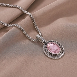Collier vintage avec pierre rose ovale et cadre floral argenté sur fond de soie