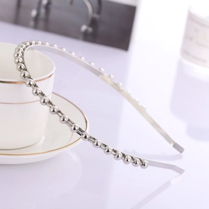 Serre-tête en métal argenté minimaliste avec perles sur fond de tasse blanche
