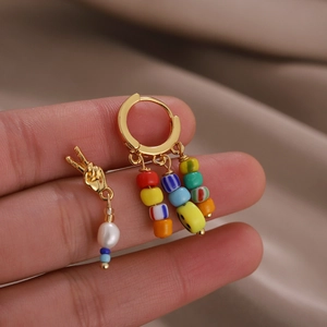 Asymmetric gold earrings with colorful beaded smiley face tassels and a peace sign charm