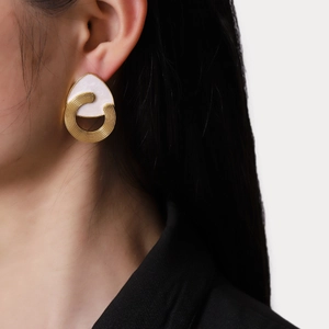 Boucles d'oreilles dorées avec nacre blanche et texture en spirale sur un mannequin