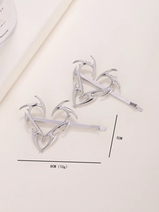 Dettaglio di due fermagli per capelli in metallo argento a forma di cuore stile Y2K